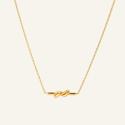 Dainty 18K gold plated necklace with infinity knot pendant on delicate chain against white background