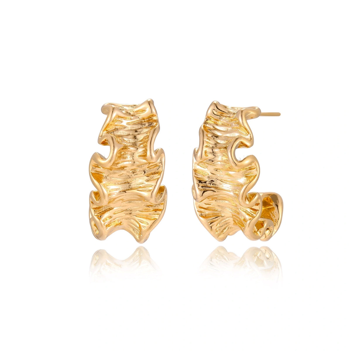Pair of gold huggie hoops with sculpted wave texture and dimensional ripples on neutral background.