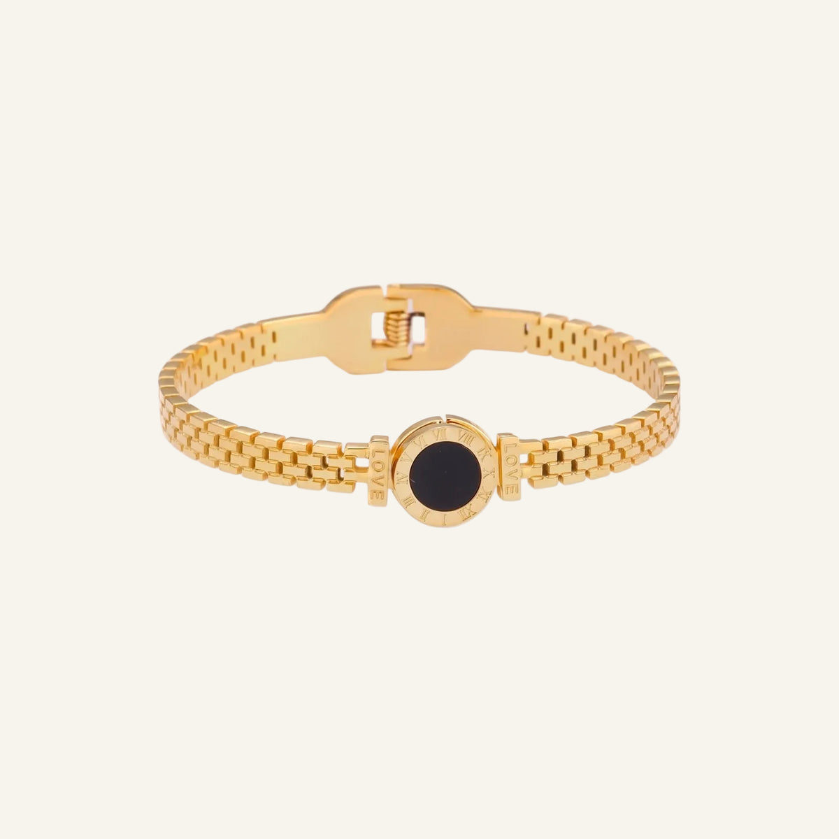 Gold mesh bracelet with circular black mother of pearl medallion featuring Roman numeral engravings and hinged clasp