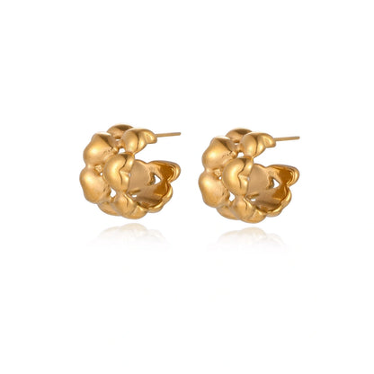 Close-up of gold-plated twisted rope huggie hoop earrings with brushed finish on white background.