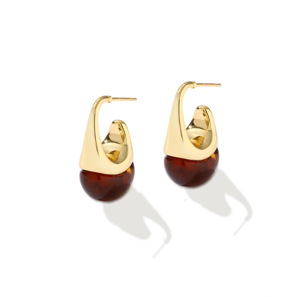Modern drop earrings with curved gold-plated copper tops and amber resin bottoms creating an organic teardrop silhouette.