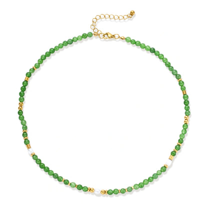 Layered necklace with green stone beads, gold spacers, white accents, and protective eye pendant on cream background.