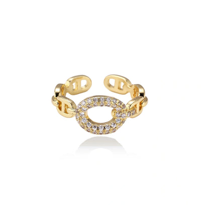 Gold-plated brass chain link ring with one oval CZ-pavé segment on cream background, adjustable cuff style.