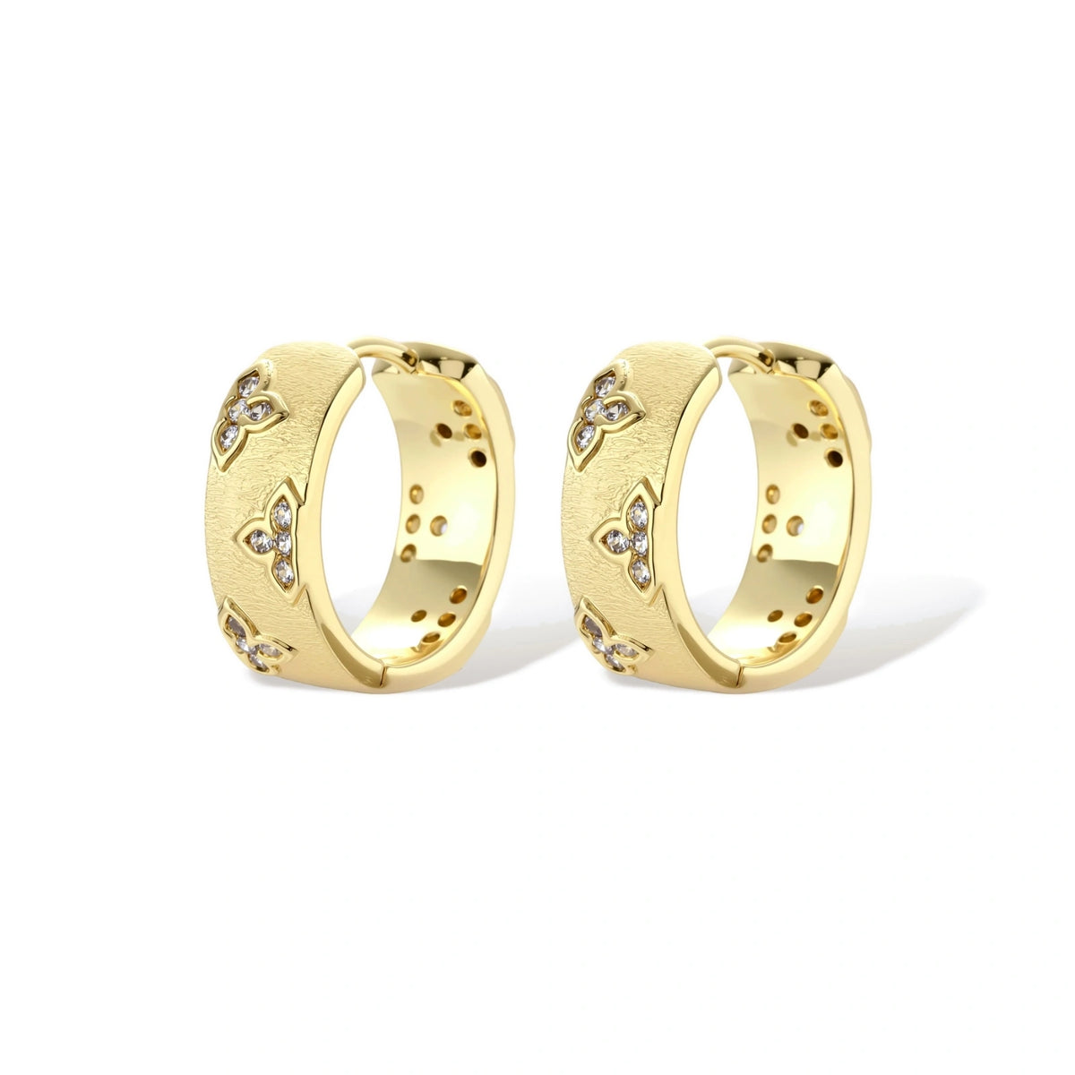 Gold-plated hoop earrings with textured surface and raised floral motifs set with clear zirconia stones on cream background.
