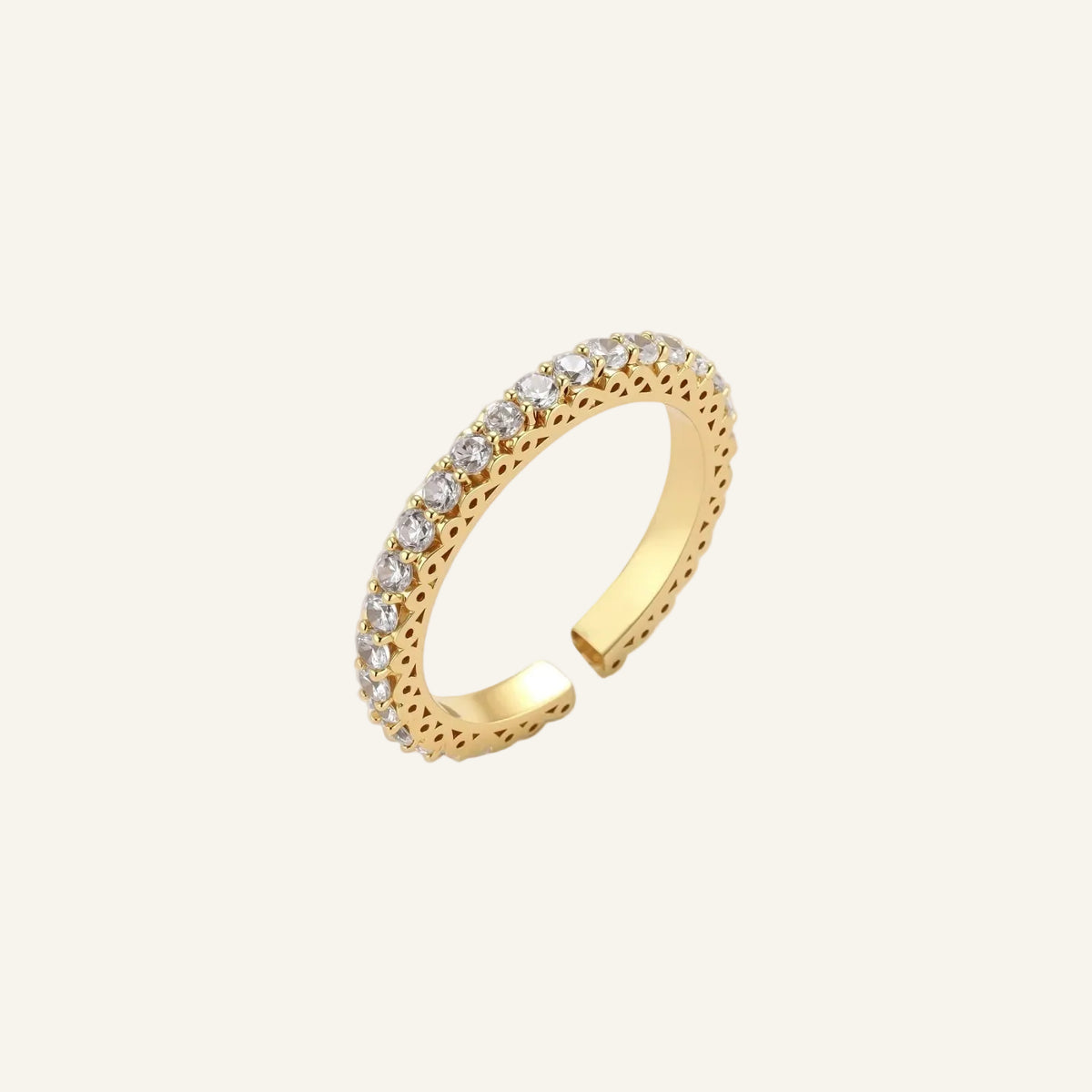 Close-up of adjustable gold-plated ring with continuous row of round zirconia stones on neutral background.