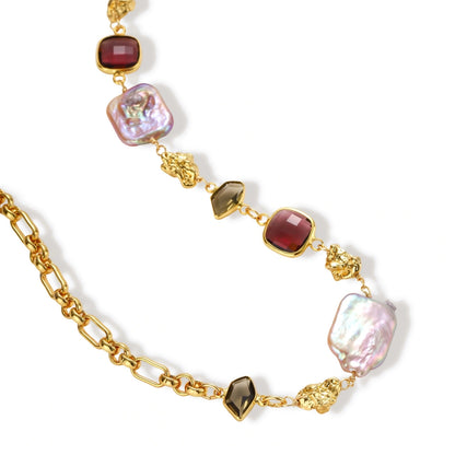 18k gold-plated chain necklace with iridescent baroque pearls and burgundy gemstones on white background.